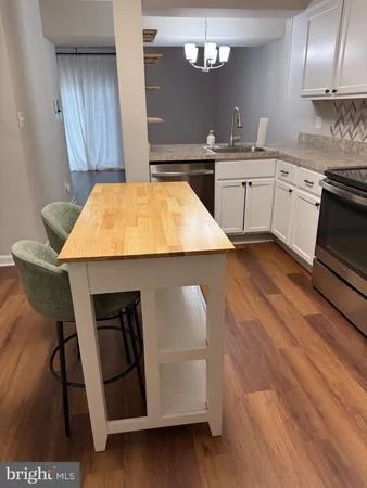 a kitchen with kitchen island stainless steel appliances a stove refrigerator sink and cabinets