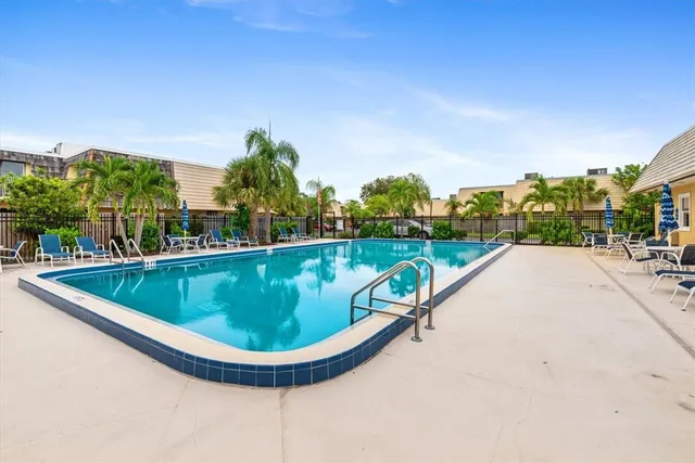 a view of swimming pool with seating area and trees in the background