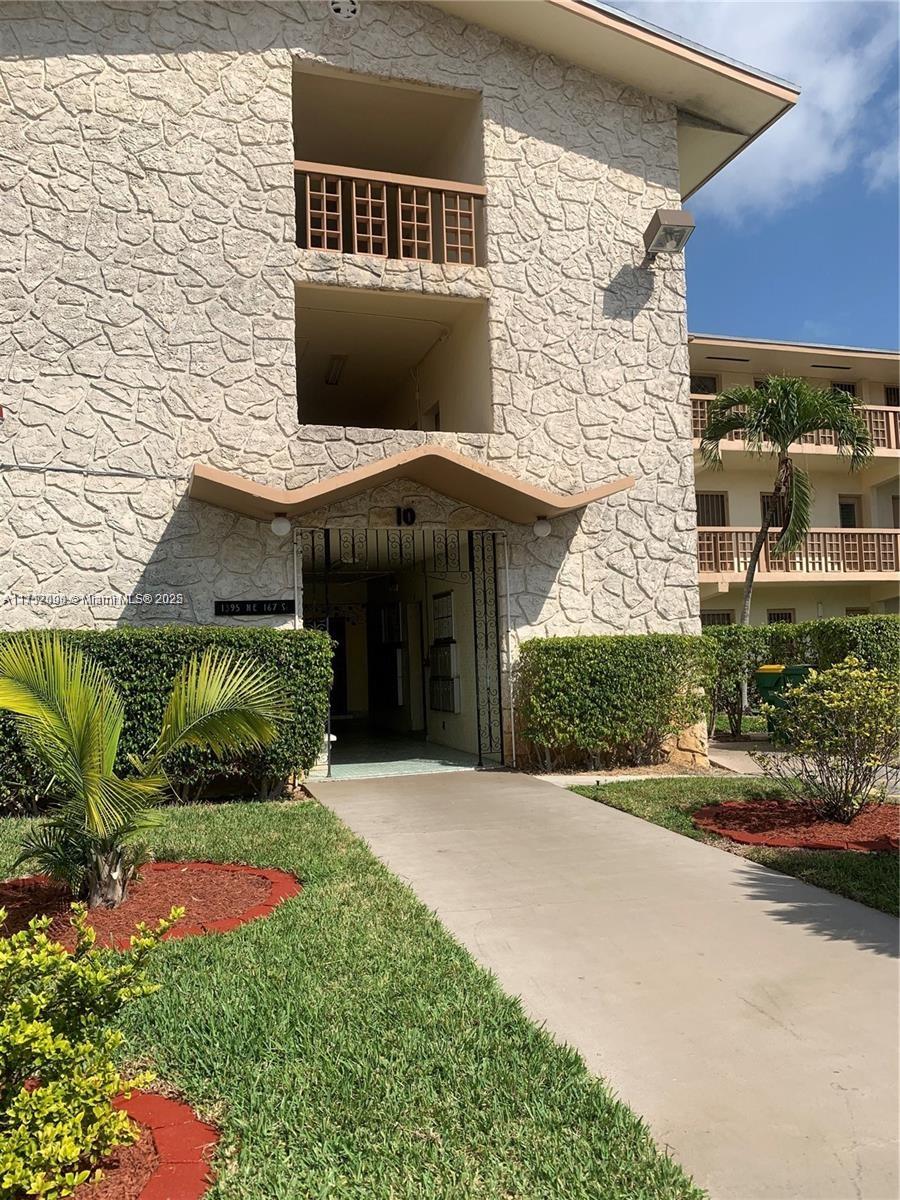 1395 Northeast 167th Street, Unit 209 Miami, FL 33162 - Photo 12 of 28 a front view of a house with a yard and garage