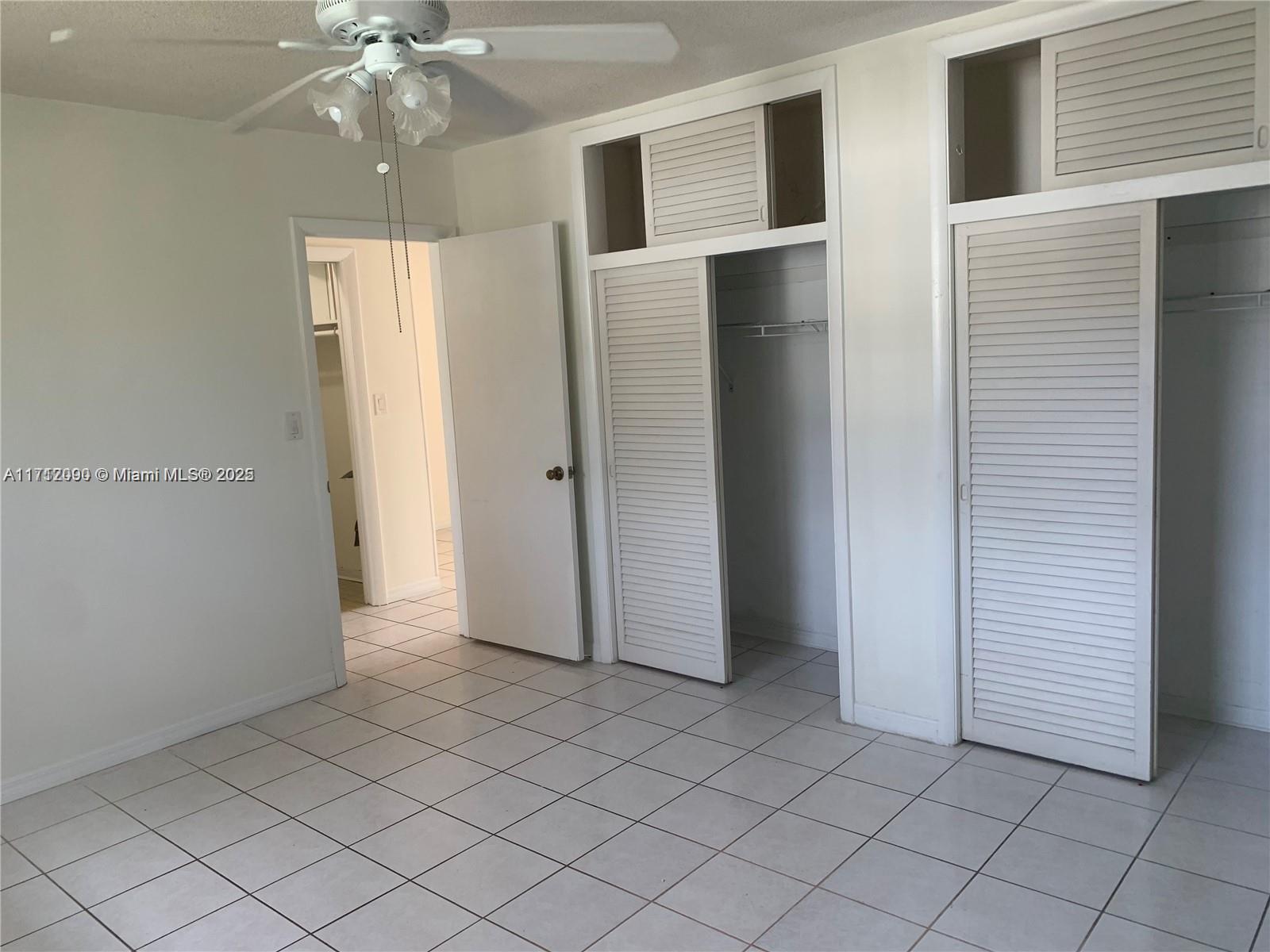 1395 Northeast 167th Street, Unit 209 Miami, FL 33162 - Photo 25 of 28 an empty room with chandelier fan and closet