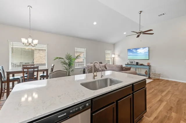 a kitchen with a sink chandelier and living room view