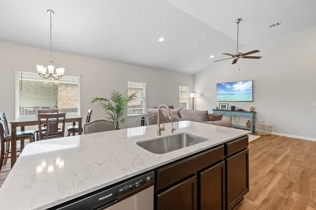 a kitchen with a sink chandelier and living room view