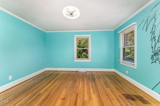 a view of an empty room with window and wooden floor