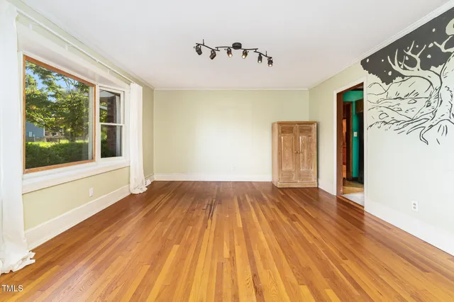 a view of an empty room with window and wooden floor