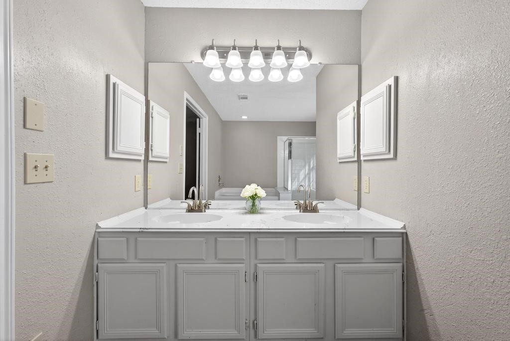 8815 Stoney Bend Drive Spring, TX 77379 - Photo 16 of 50 This bathroom features a double vanity with a large mirror and modern lighting. The neutral color scheme and white cabinetry create a clean, spacious feel.