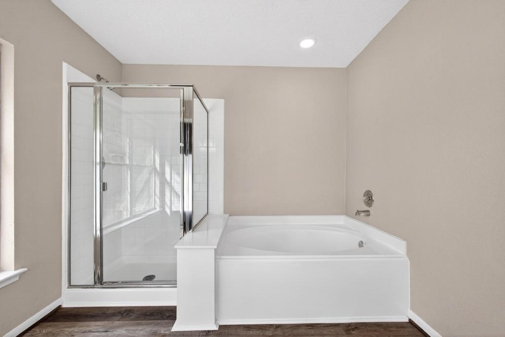8815 Stoney Bend Drive Spring, TX 77379 - Photo 17 of 50 This bathroom features a modern design with a glass-enclosed shower and a spacious white soaking tub. The neutral walls and wood-look flooring create a warm, inviting atmosphere.