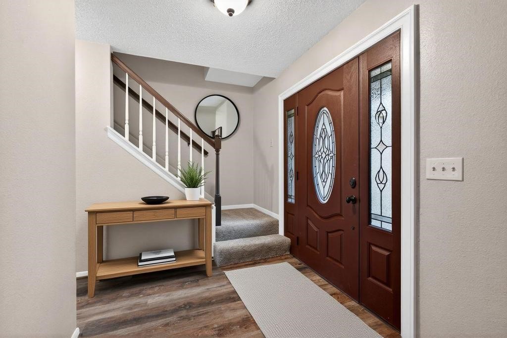 8815 Stoney Bend Drive Spring, TX 77379 - Photo 2 of 50 This inviting entryway features a wooden front door with glass panels, a staircase with white spindles, and a cozy carpeted landing.