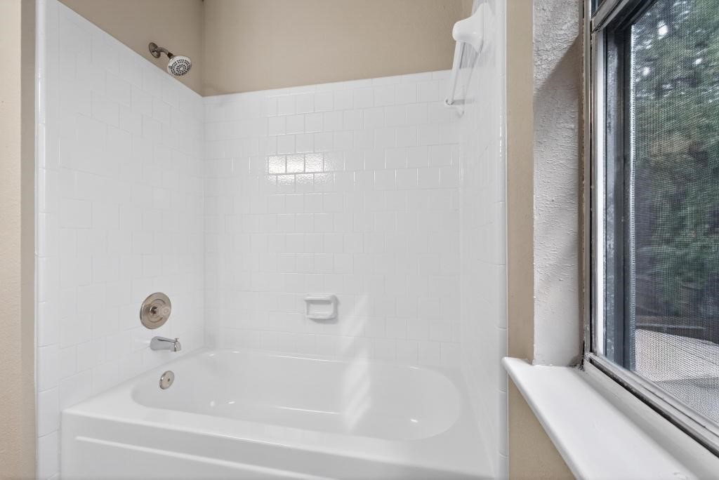 8815 Stoney Bend Drive Spring, TX 77379 - Photo 25 of 50 This bathroom features a clean, white tiled shower and bathtub combo with a window providing natural light.