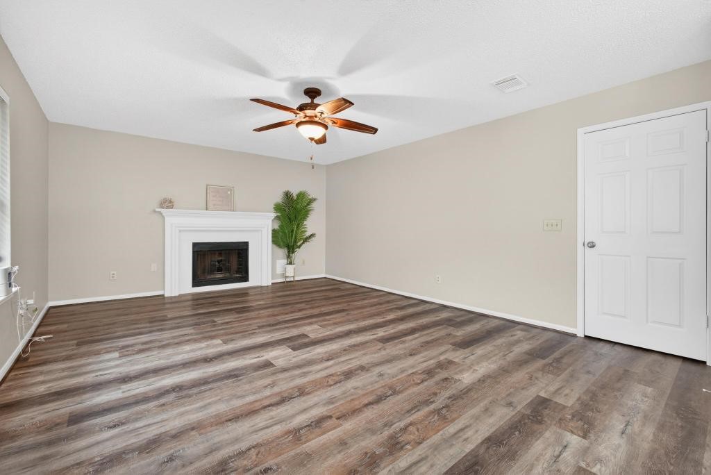 8815 Stoney Bend Drive Spring, TX 77379 - Photo 5 of 50 Bright living room with neutral walls, featuring a cozy fireplace, ceiling fan, and stylish flooring—ideal for relaxation and entertaining.