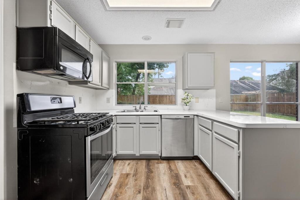 8815 Stoney Bend Drive Spring, TX 77379 - Photo 7 of 50 Bright and modern kitchen featuring stainless steel appliances, sleek countertops, and ample natural light from large windows overlooking the backyard. Neutral cabinetry and light flooring create a warm, inviting space.