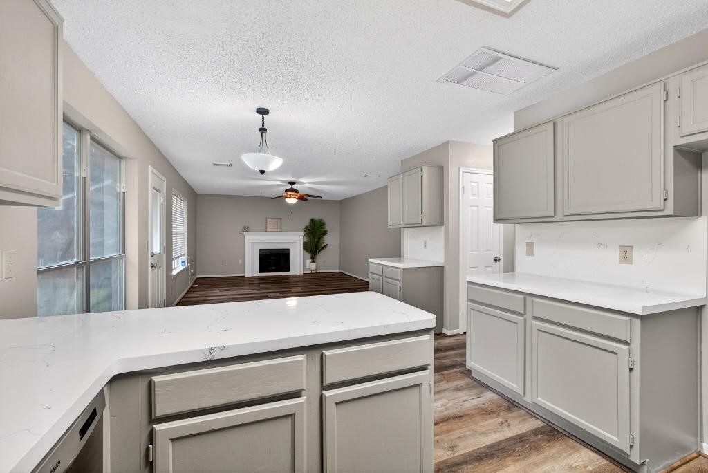 8815 Stoney Bend Drive Spring, TX 77379 - Photo 8 of 50 This photo showcases a spacious, open-concept kitchen and living area. The kitchen features light-colored cabinetry and modern countertops, with a seamless flow into the living room, which includes a cozy fireplace and ample natural light from large windows. Perfect for entertaining.
