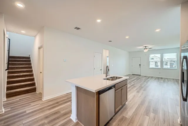 a kitchen with stainless steel appliances granite countertop a stove a sink and a refrigerator with wooden floor