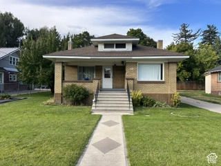 481 East Center Street Logan, UT 84321 - Photo 1 of 23 Brick facade with a dormer window, covered front porch, concrete steps, and a patterned walkway