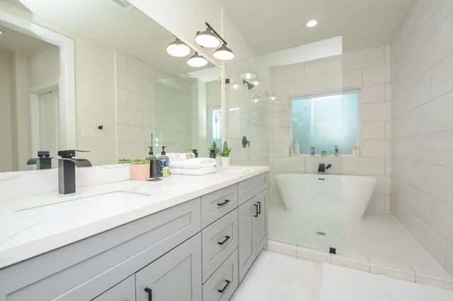a bathroom with a double vanity sink mirror and bathtub