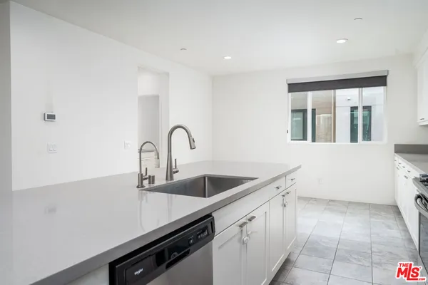 a kitchen with granite countertop white cabinets and window