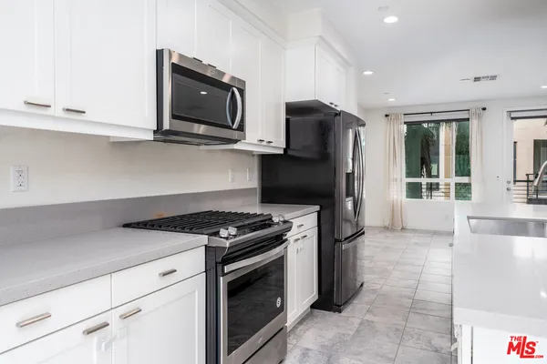 a large white kitchen with stainless steel appliances granite countertop a large counter top and a stove top oven