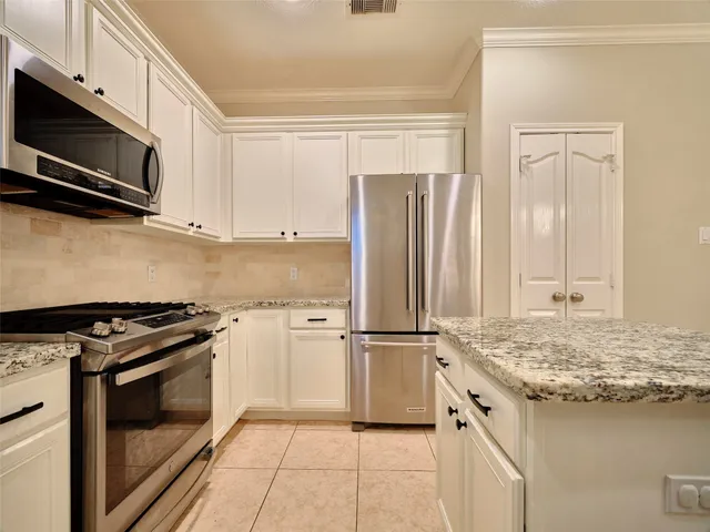 a kitchen with stainless steel appliances granite countertop a stove a refrigerator and a microwave