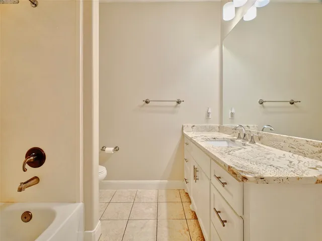 a bathroom with a granite countertop sink a toilet and shower