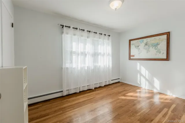 a view of an empty room with window and wooden floor