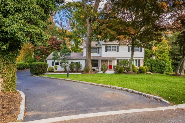 a view of a house with a yard and large trees