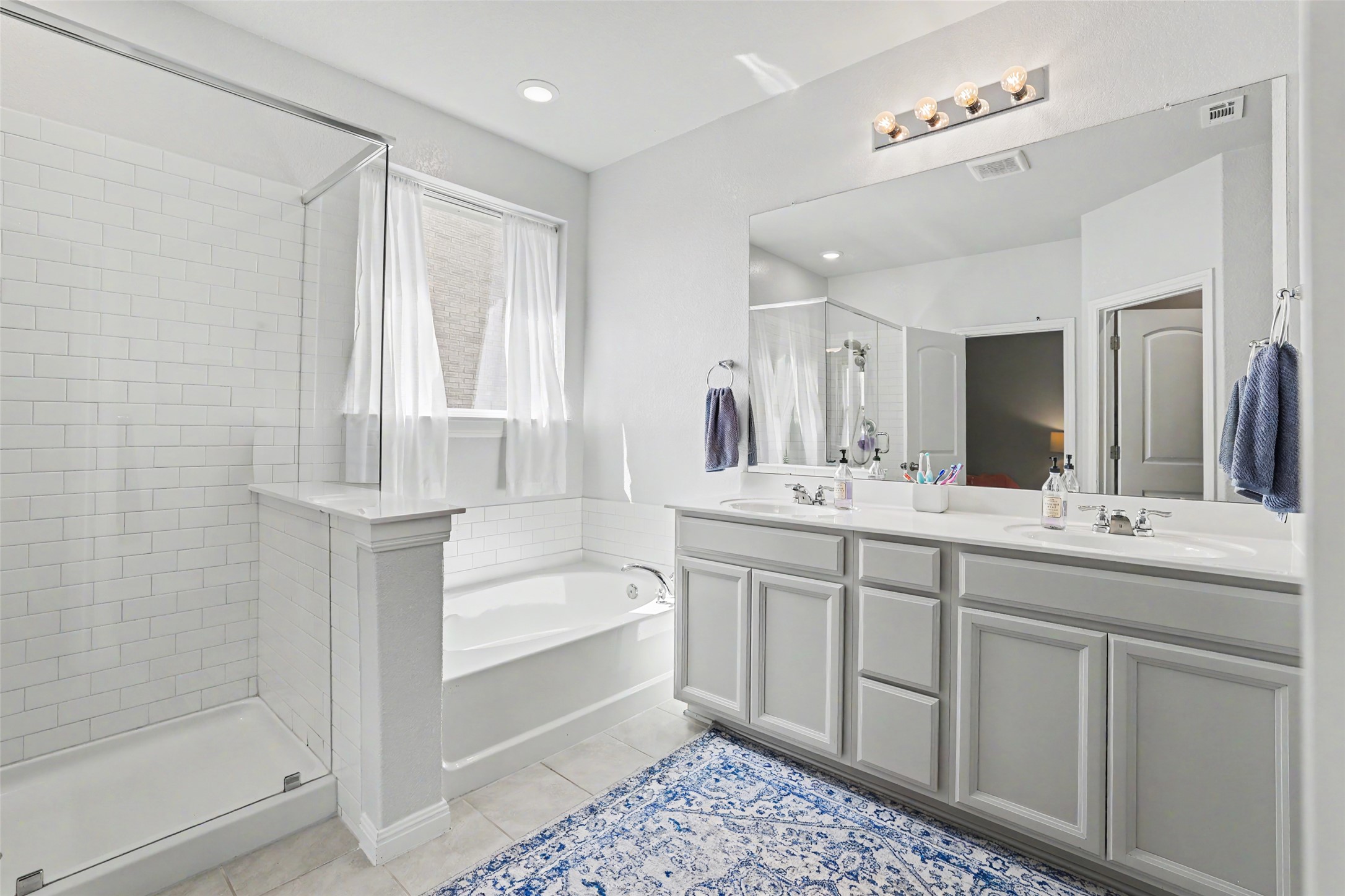112 Rocking R Court Georgetown, TX 78633 - Photo 19 of 40 A well-lit bathroom features a spacious vanity with dual sinks, a large soaking tub, and a separate glass-enclosed shower.