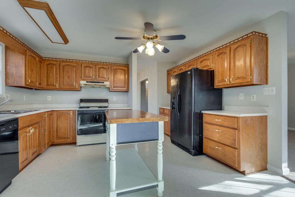 639 Vaughan's Gap Road Spring Hill, TN 37174 - Photo 7 of 19 a kitchen with granite countertop wooden cabinets and stainless steel appliances