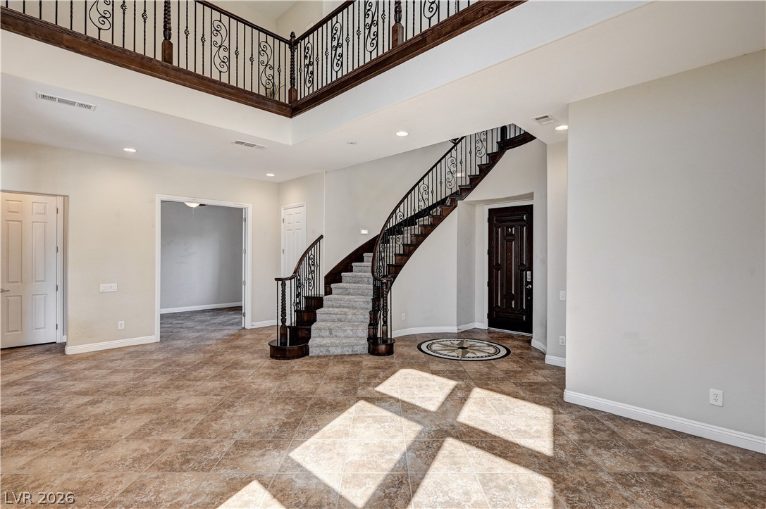 2793 Rosenhearty Drive Henderson, NV 89044 - Photo 22 of 85 A grand entrance welcomes with a winding staircase and tiled flooring, bathed in natural light.