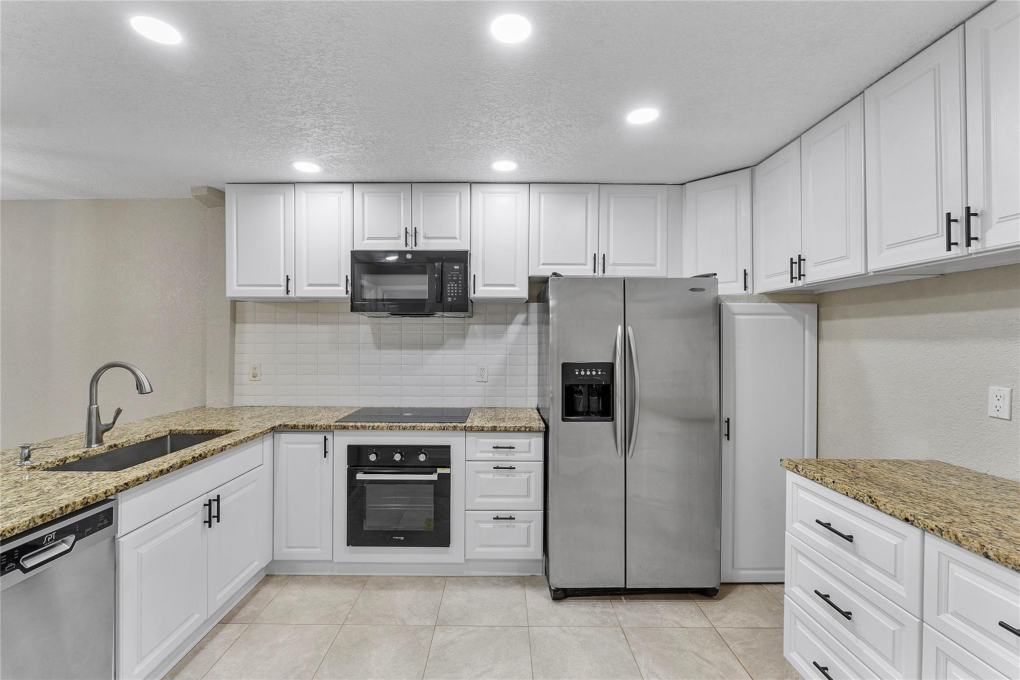 5290 Gate Lake Road, Unit 5290 Tamarac, FL 33319 - Photo 8 of 18 a kitchen with granite countertop white cabinets and stainless steel appliances