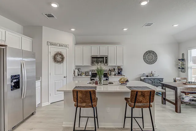 a kitchen with refrigerator and chairs