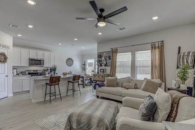 a living room with furniture kitchen view and a large window