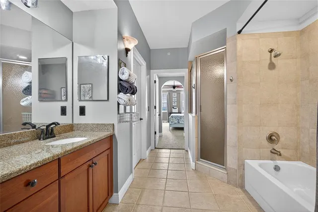 a spacious bathroom with a granite countertop sink a mirror a bathtub and shower