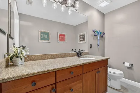a bathroom with a granite countertop sink a toilet and mirror