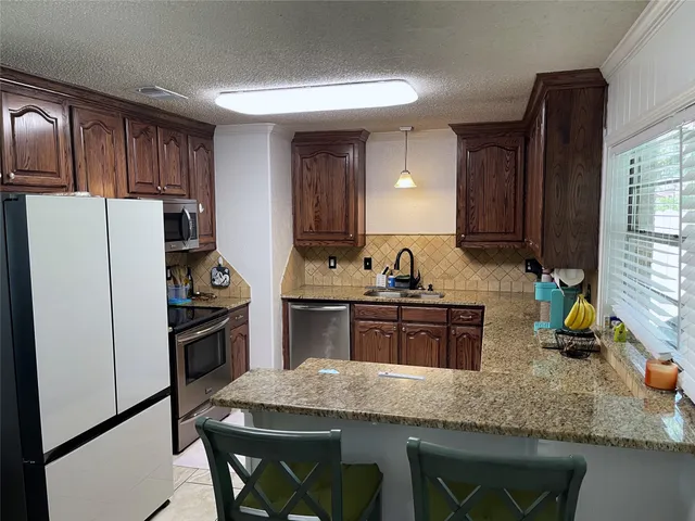 a kitchen with granite countertop a refrigerator stove microwave and sink