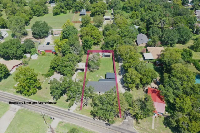 an aerial view of residential house with outdoor space and trees all around
