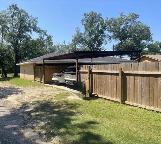 a view of backyard with wooden fence and large trees