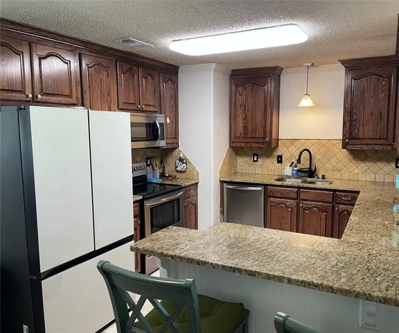 a kitchen with granite countertop stainless steel appliances and wooden cabinets