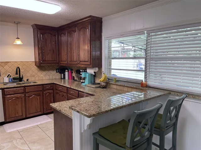 a kitchen with granite countertop kitchen island stainless steel appliances a sink stove and cabinets