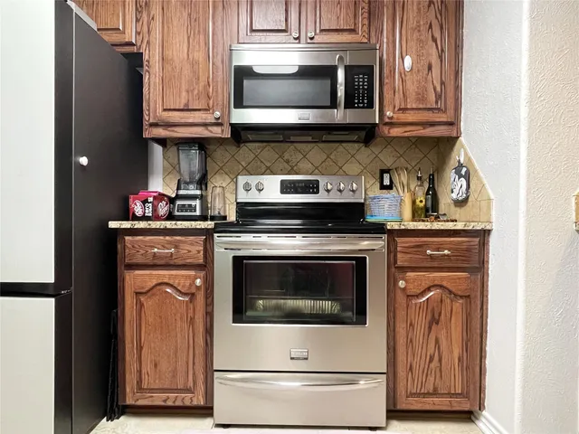 a kitchen with granite countertop a stove top oven microwave and cabinets