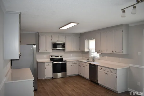 a kitchen with a sink white cabinets and stainless steel appliances