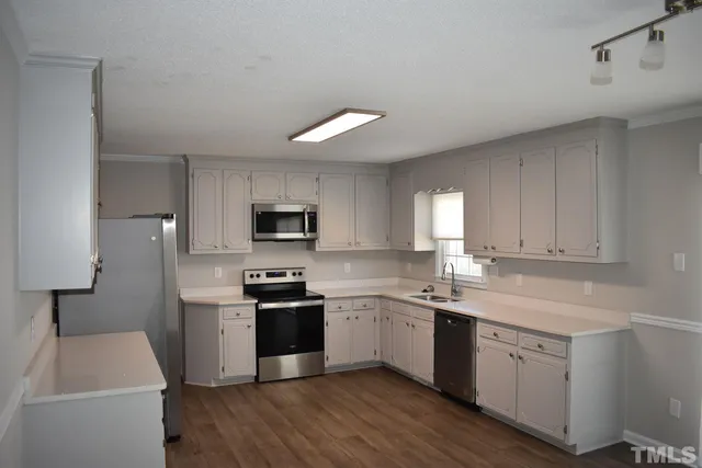 a kitchen with a sink white cabinets and stainless steel appliances