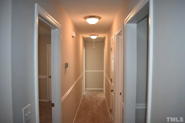 a view of a hallway with wooden floor and a bathroom