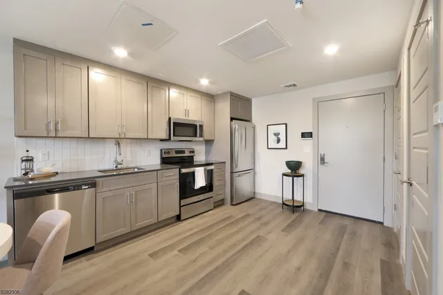 a kitchen with granite countertop a sink cabinets stainless steel appliances and a counter top space
