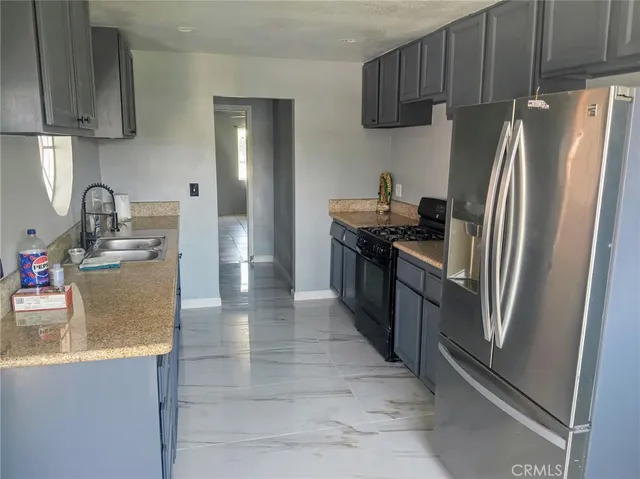 a kitchen with stainless steel appliances granite countertop a refrigerator a stove and a sink