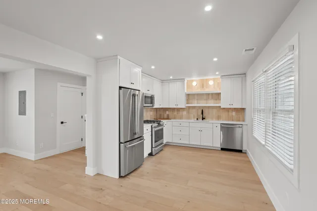 a kitchen with a refrigerator and white cabinets