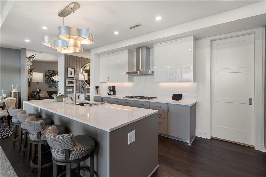 2425 Peachtree Street Northeast, Unit 707 Atlanta, GA 30305 - Photo 5 of 39 a kitchen with stainless steel appliances granite countertop a sink a stove a refrigerator and island with wooden floor