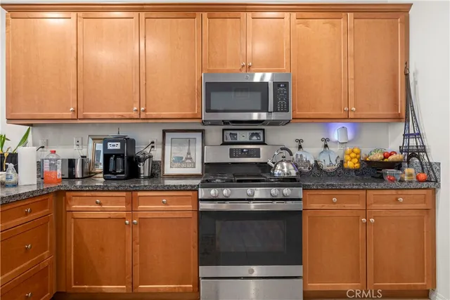 a kitchen with stainless steel appliances granite countertop a refrigerator and a stove top oven