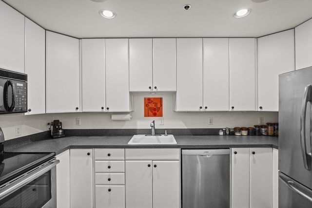 a kitchen with granite countertop white cabinets and stainless steel appliances