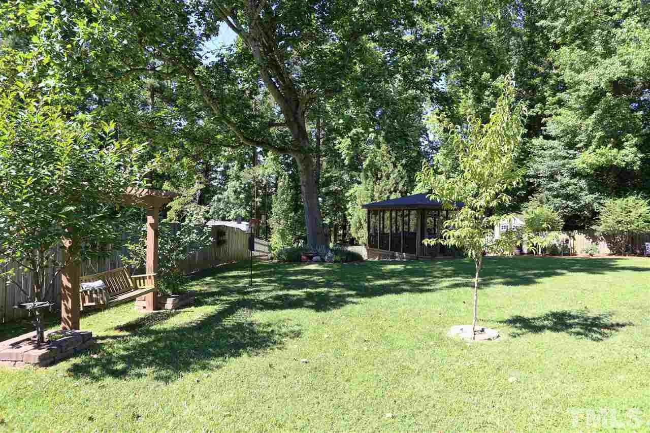 1809 Albacore Lane Raleigh, NC 27612 - Photo 21 of 25 a backyard of a house with plants and large trees