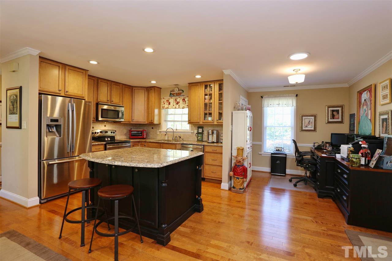 1809 Albacore Lane Raleigh, NC 27612 - Photo 8 of 25 a kitchen with stainless steel appliances granite countertop a refrigerator a stove top oven and a dining table with wooden floor