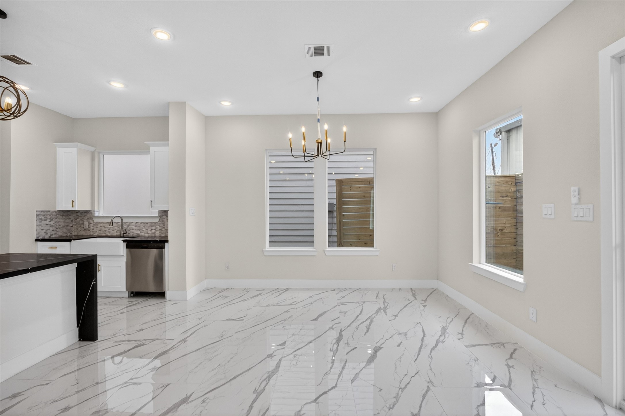 5906 St Augustine Street, Unit F Houston, TX 77021 - Photo 5 of 34 Light-filled dining area beside the kitchen with a chandelier, marble-look flooring, and multiple windows.